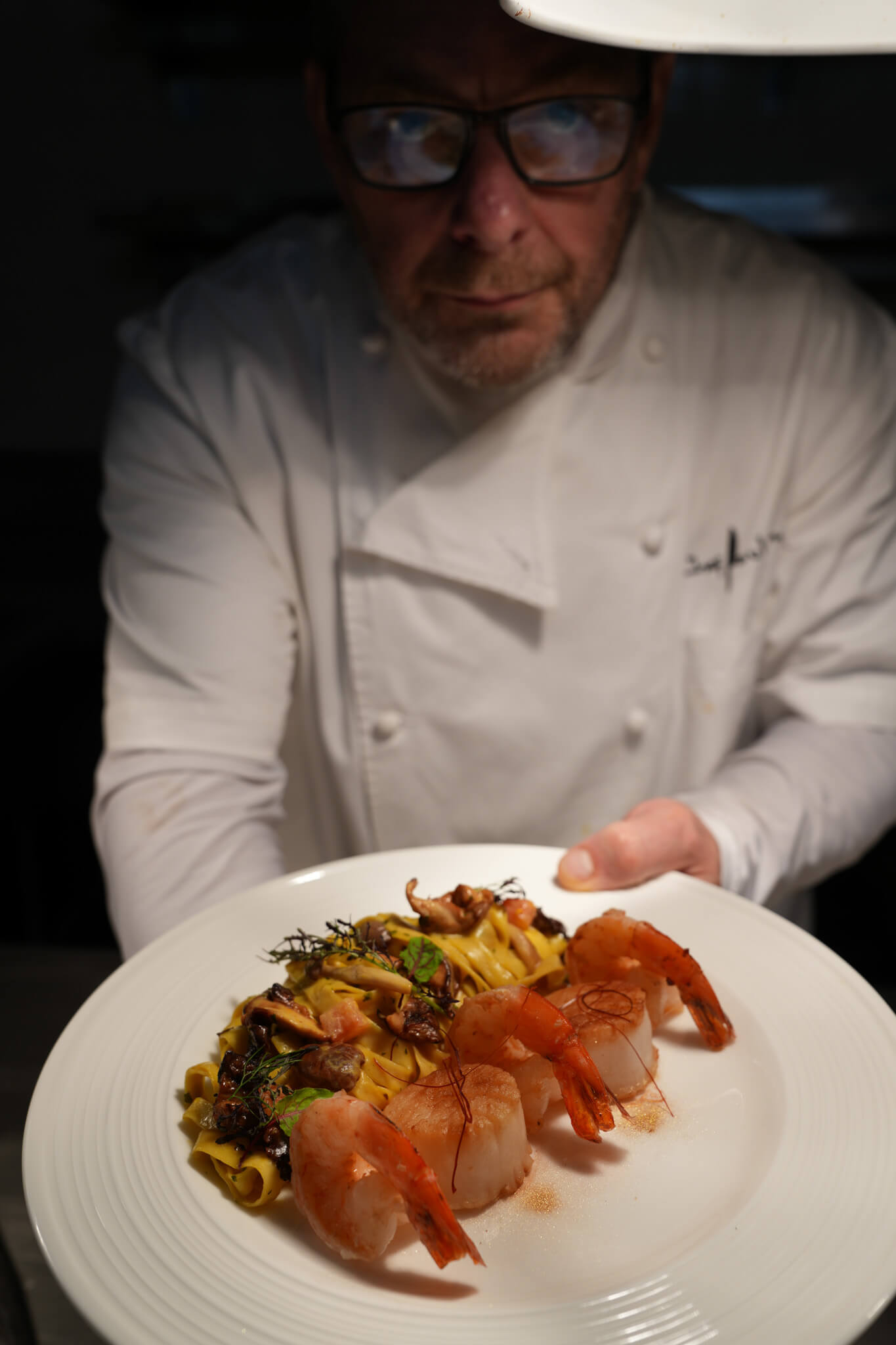 Chef Paul Syms plating a gourmet dish with professional technique